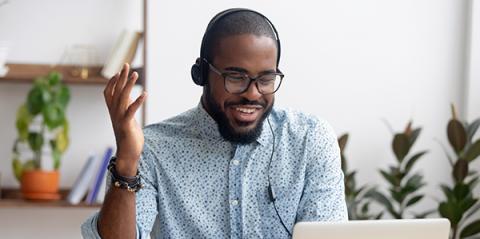 A man talking on the phone via headset while working on a laptop