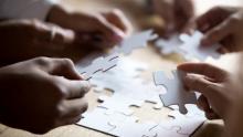 Close-up photo of multiple people's hands putting a puzzle together